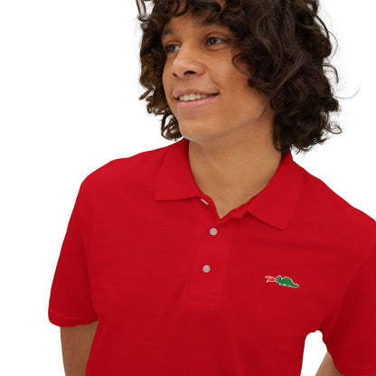 A person with curly hair wearing a navy blue Printify Braggin' Dragon - 1980s Sears Men's Piqué Polo, featuring a small embroidered dragon logo on the left chest, smiles against a plain white background.