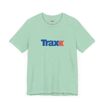 A gray unisex jersey short sleeve tee from Printify, inspired by retro 1980s Kmart style. The "Trax" logo is printed in blue letters, followed by three red arrows pointing to the right. This classic Trax Brand T-shirt is laid flat against a white background, capturing nostalgic fashion vibes.