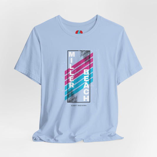 The Printify Miller Beach 1980s Style Unisex Jersey Short Sleeve Tee features a light blue base with retro-inspired diagonal stripes in blue and pink. "Miller Beach" is vertically displayed in white alongside black palm leaves, with "Gary Indiana" written at the bottom.