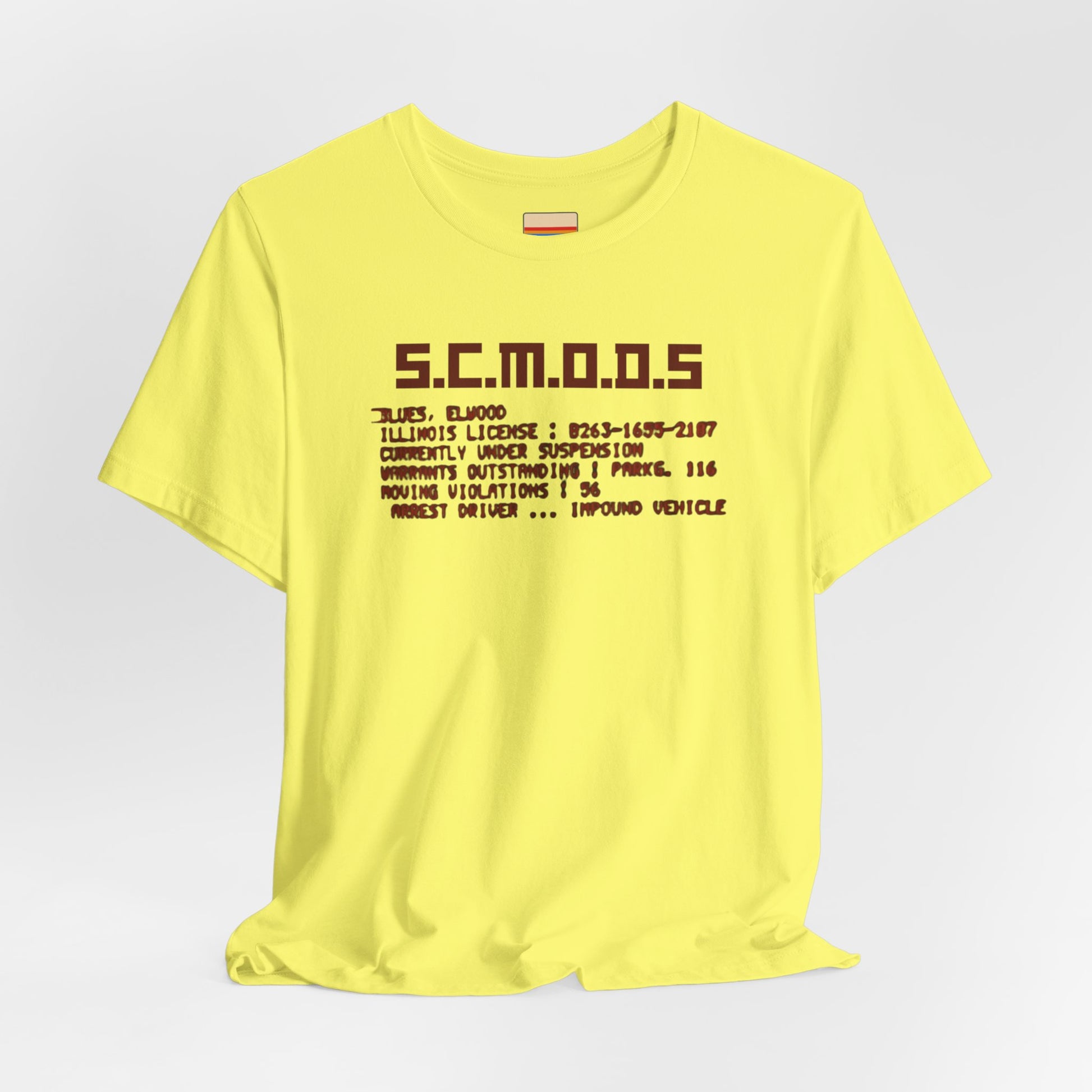 Two yellow "S.C.M.O.D.S. Blues Brother's - Unisex Jersey Short Sleeve Tee" shirts from Printify, featuring "S.C.M.O.D.S" in bold, stylized letters along with smaller text detailing terms like "Illinois," "license," and "impound vehicle." Perfect for fans of The Blues Brothers and Jake and Elwood Blues, the T-shirts are neatly folded and stacked.