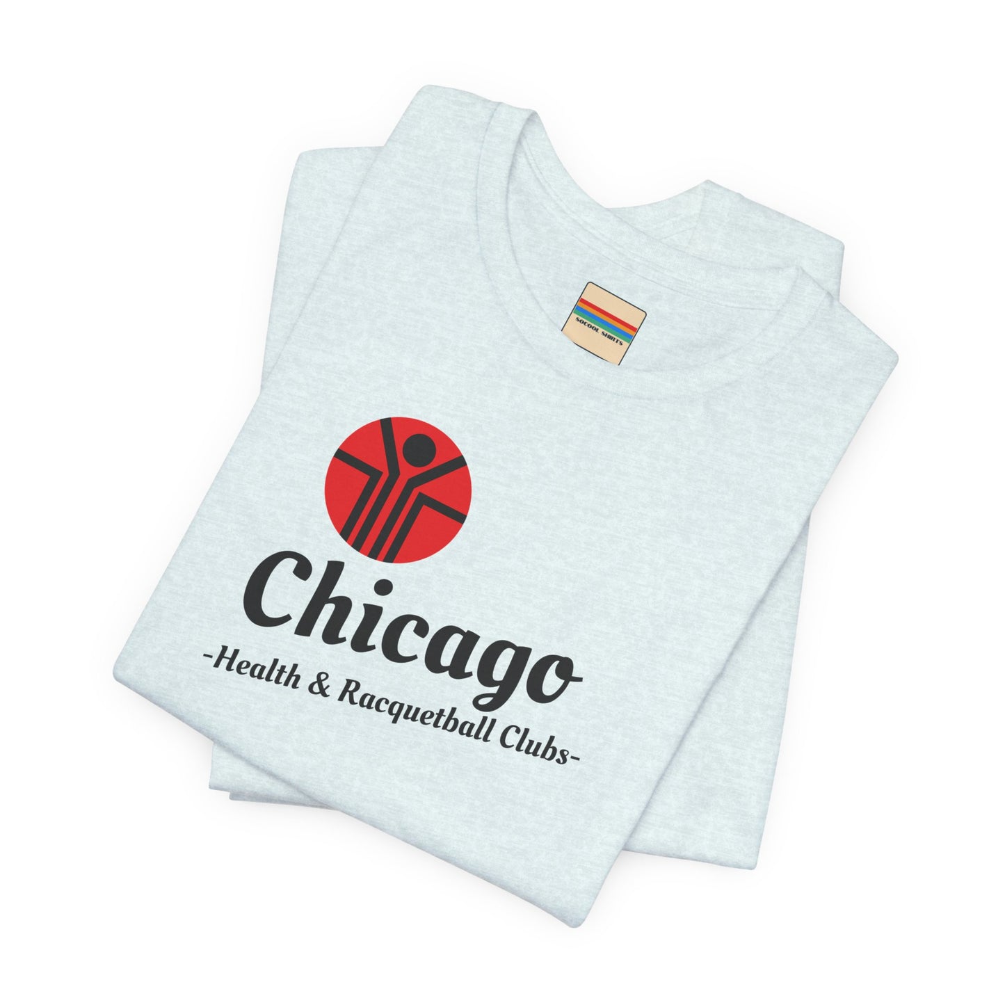 Two gray T-shirts are neatly folded on top of each other, with the top shirt showcasing the text "Chicago Health & Racquetball Clubs" in black below a red logo featuring a person with raised arms inside a circular design. This retro-inspired tee, named "Chicago Health Clubs 1980s Retro - Unisex Jersey Short Sleeve Tee" by Printify, is perfect for any fan of Chicago Health Clubs.