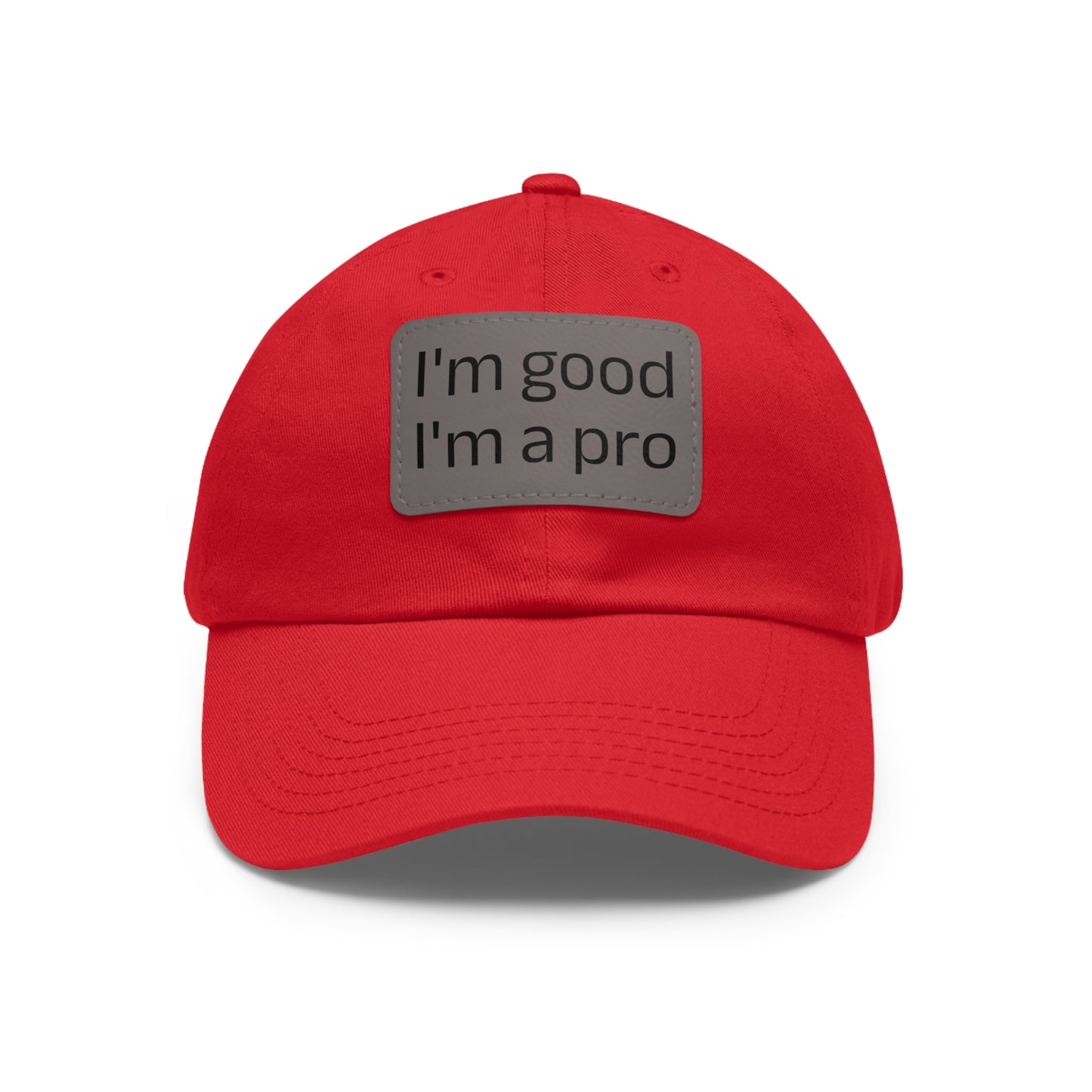 The Printify Dad Hat with Leather Patch (Rectangle) is a black, six-panel low-profile baseball cap made from bio-washed chino twill. This personalized Dad hat features a curved brim, visible stitching details, and a rectangular leather patch on the front that reads "I'm good I'm a pro" in grey text.