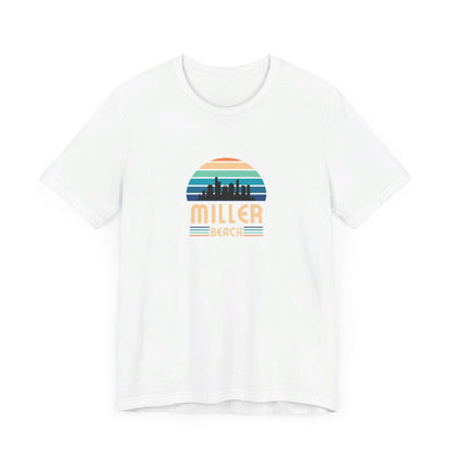 A brown unisex jersey short sleeve tee called "Miller Beach Chicago Skyline" from Printify features a vintage-style design with a sunset, the Chicago skyline, and "Miller Beach" in bold letters. The design incorporates shades of blue, orange, and yellow and is displayed against a plain white background.