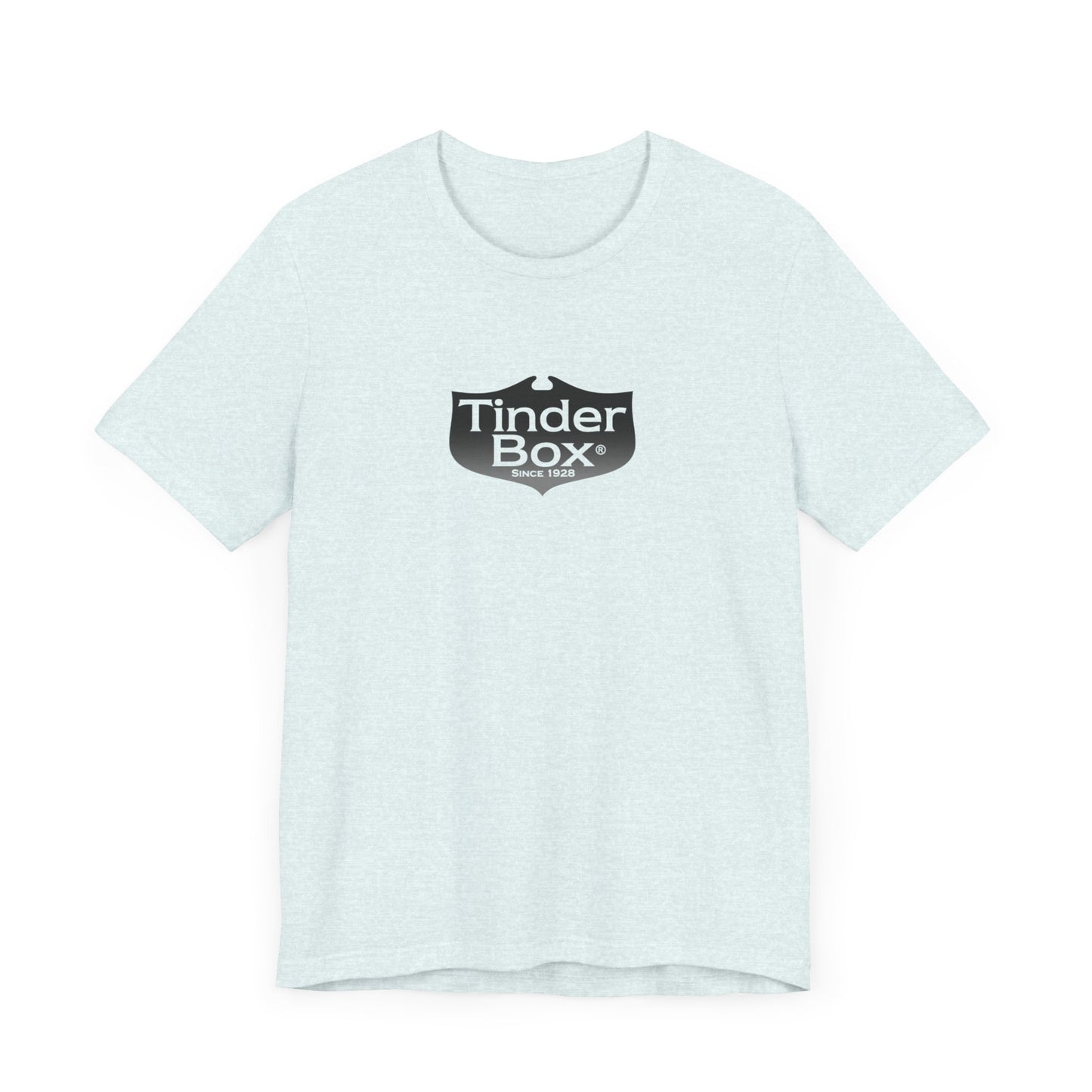 A light blue Printify "The Tinder Box 1980s" unisex jersey short sleeve tee featuring the "Tinder Box" logo in the center. The logo consists of a dark shield with the words "Tinder Box" in white text, with a small flame icon replacing the dot above the "i".