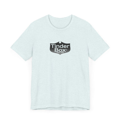 A light blue Printify "The Tinder Box 1980s" unisex jersey short sleeve tee featuring the "Tinder Box" logo in the center. The logo consists of a dark shield with the words "Tinder Box" in white text, with a small flame icon replacing the dot above the "i".
