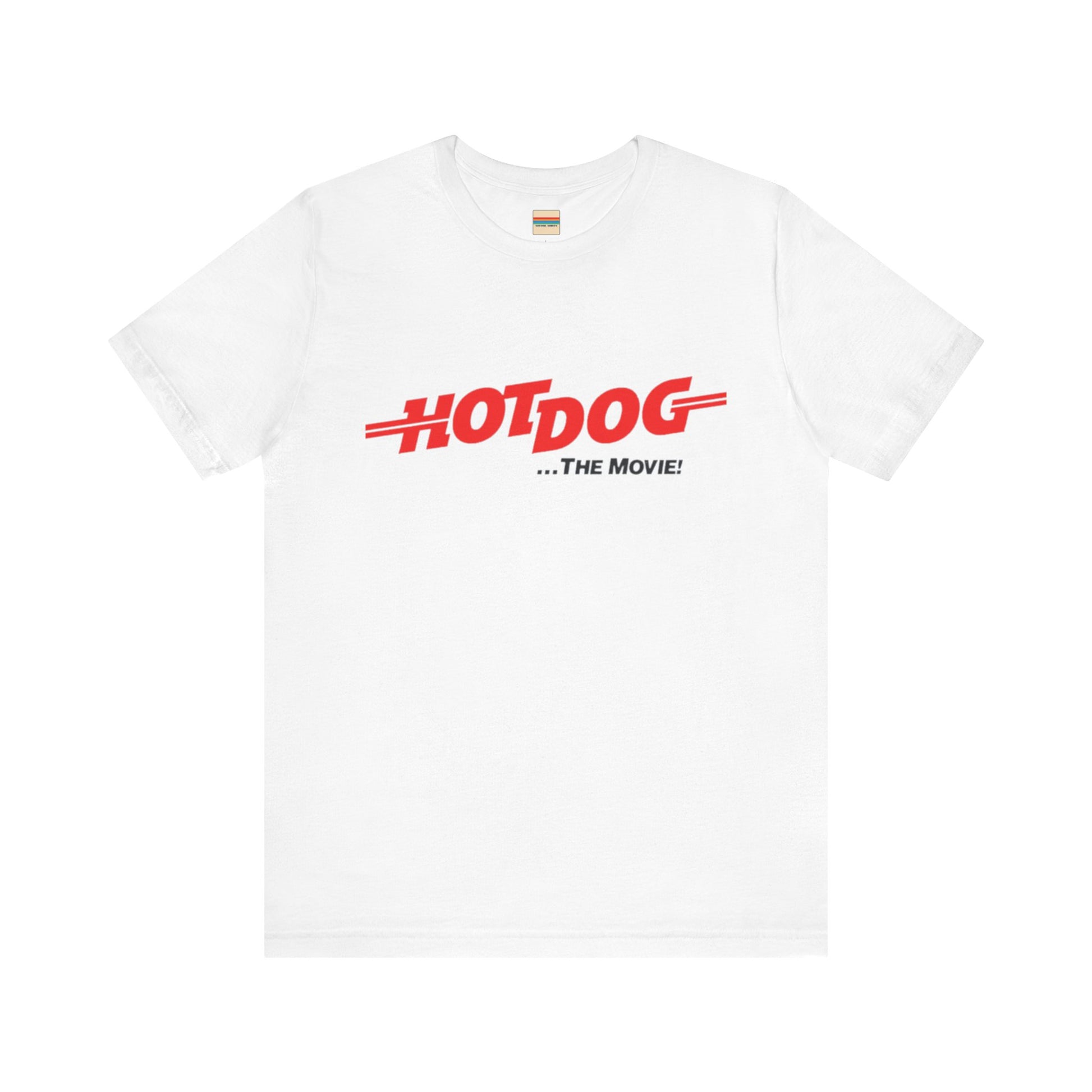 A smiling man and woman interact while wearing matching yellow "Hot Dog The Movie 1984 - Unisex Jersey Short Sleeve Tee" by Printify, featuring bold red "HOT DOG THE MOVIE" text. Their vibrant tees perfectly complement their blue jeans, with the man casually having his hands in his pockets and the woman resting one hand on his shoulder.