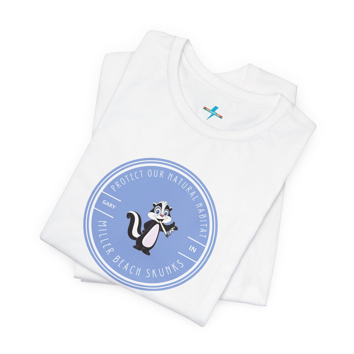 The Printify Miller Beach Skunks - Unisex Jersey Short Sleeve Tee is a gray T-shirt that features a circular blue logo at the center. Inside the logo, there is an illustration of a skunk with the text "Protect Our Habitat" and "Miller Beach Skunks" around the border, promoting environmental consciousness. The upper left part of the logo reads "Gary, IN.