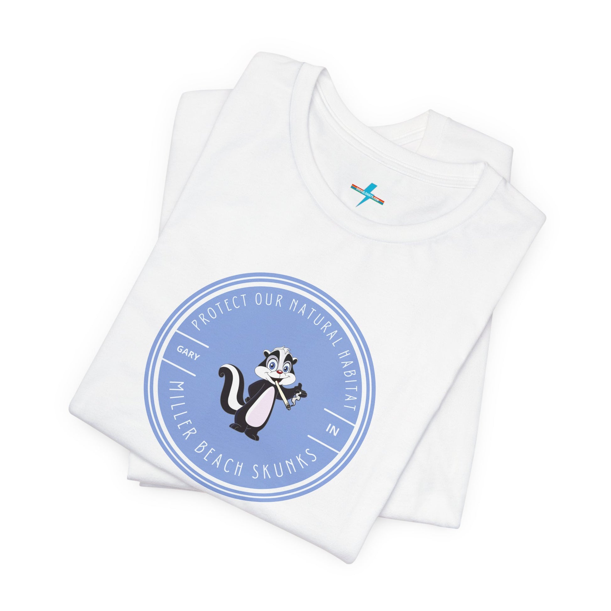 The Printify Miller Beach Skunks - Unisex Jersey Short Sleeve Tee is a gray T-shirt that features a circular blue logo at the center. Inside the logo, there is an illustration of a skunk with the text "Protect Our Habitat" and "Miller Beach Skunks" around the border, promoting environmental consciousness. The upper left part of the logo reads "Gary, IN.