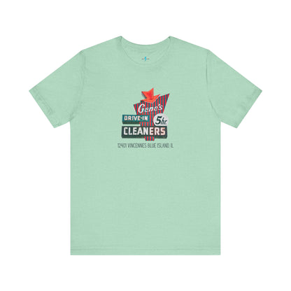 A unisex Jersey short sleeve tee from Printify featuring a light grey color with a retro-style graphic in the center. The design showcases text that reads "Gene's Drive In Cleaners, 5th," along with the address "12401 Vincennes Blue Island IL" in a blend of vintage fonts and colors, evoking the classic Chicago Fire-era vintage sign aesthetic.