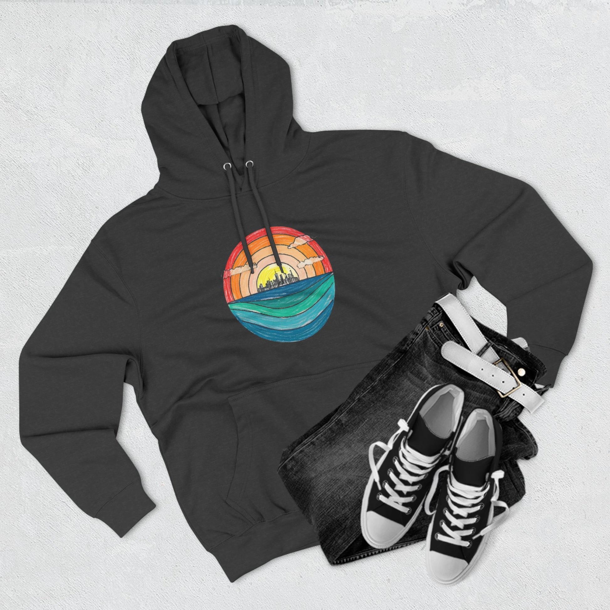 The Miller Beach Abstract - Three-Panel Fleece Hoodie by Printify is a premium light gray pullover featuring a vibrant circular front design. It showcases an abstract sunset-over-ocean scene with blue waters, an orange to red gradient sky, and a city skyline silhouette. Made from soft combed ring-spun cotton and lined with cozy fleece for extra warmth.