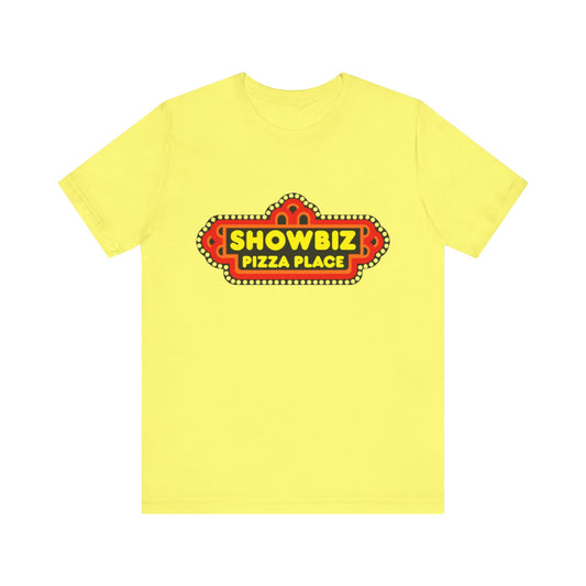 The Showbiz Pizza Place 1980s unisex jersey short sleeve tee from Printify is a yellow t-shirt made from Airlume combed cotton. It features a colorful vintage-style sign on the front with the text "Showbiz Pizza Place" in bold letters, surrounded by a red and orange border with a series of small white dots. Combining retro charm with sustainable manufacturing, this classic tee is perfect for anyone looking to add a touch of nostalgia to their wardrobe.