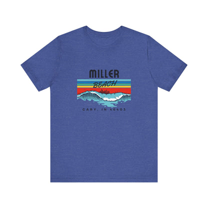 The Miller Beach 46403 Surf Style - Unisex Jersey Short Sleeve Tee by Printify features a retro surf-inspired design on a yellow background. The shirt displays "MILLER BEACH" above waves with a skyline illustration, while "Cary, IN 46403" is printed below the waves. The vibrant design also includes colorful stripes in shades of blue, red, and orange.