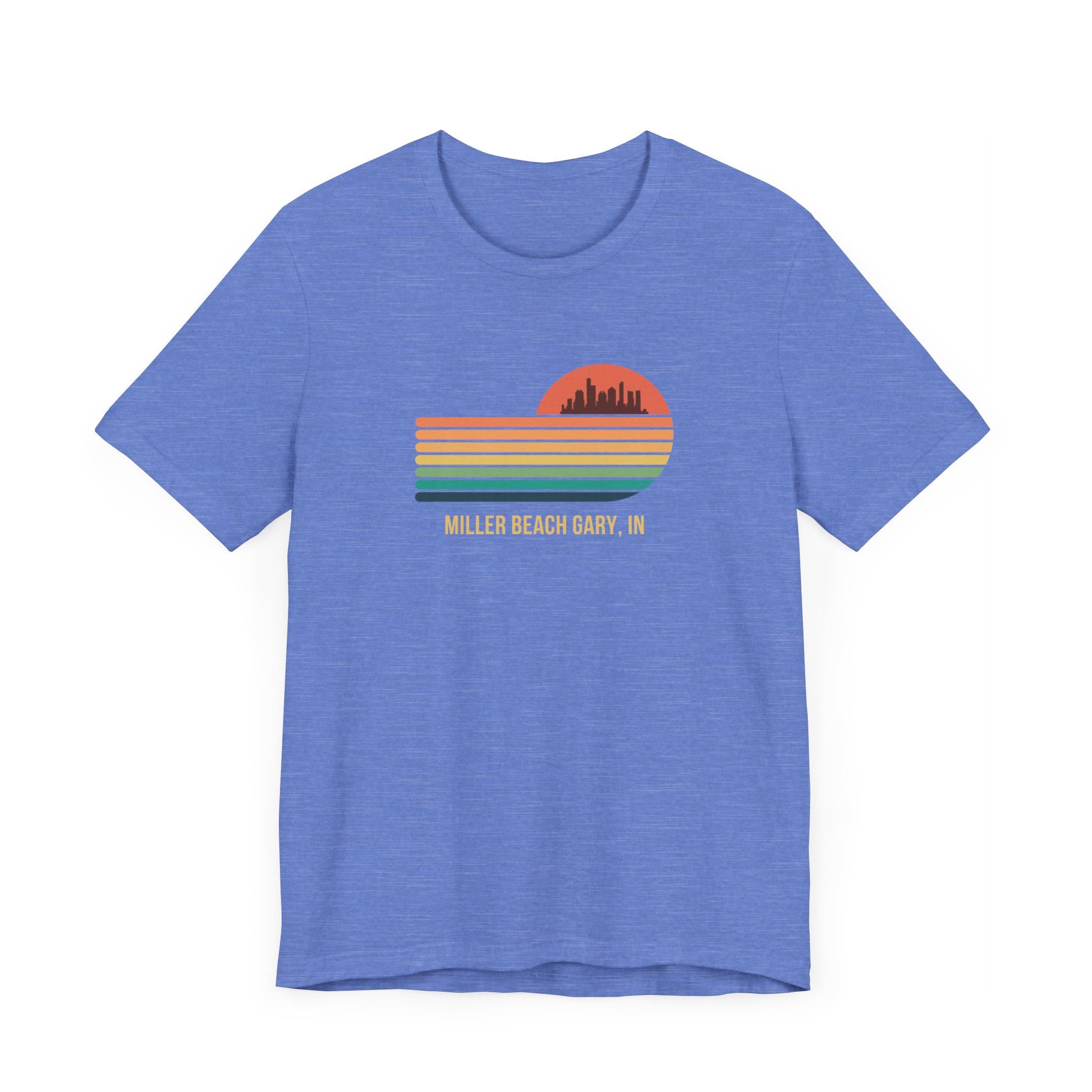 Introducing the Miller Beach Gary, IN Sunset Gradient - Unisex Jersey Short Sleeve Tee by Printify. This stylish blue T-shirt features a circular sunset graphic on the chest, showcasing a black city skyline silhouette against an orange-red sunset with horizontal stripes in green, yellow, and orange. Below the graphic reads "MILLER BEACH GARY, IN." Crafted from soft cotton for extra beachy charm.