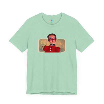 The rust-colored Printify Lady Elaine - Mr. Rogers Unisex Jersey Short Sleeve Tee features a detailed image of the Lady Elaine puppet, dressed in a red outfit with a painted face, set against an intricate artistic backdrop. The centrally positioned puppet and vivid colors create a striking contrast against the muted tone of the shirt, evoking nostalgic memories of Mr. Rogers' Neighborhood.