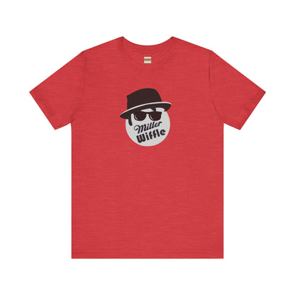 A purple unisex jersey tee from Printify, named the "Miller Wiffel Ball - Blues Brothers - Unisex Jersey Short Sleeve Tee," features a stylized graphic of a ball wearing a black fedora and sunglasses with the text "Miller Wiffel" below it. Another identical soft cotton t-shirt is neatly folded underneath, highlighting its breathable fabric.