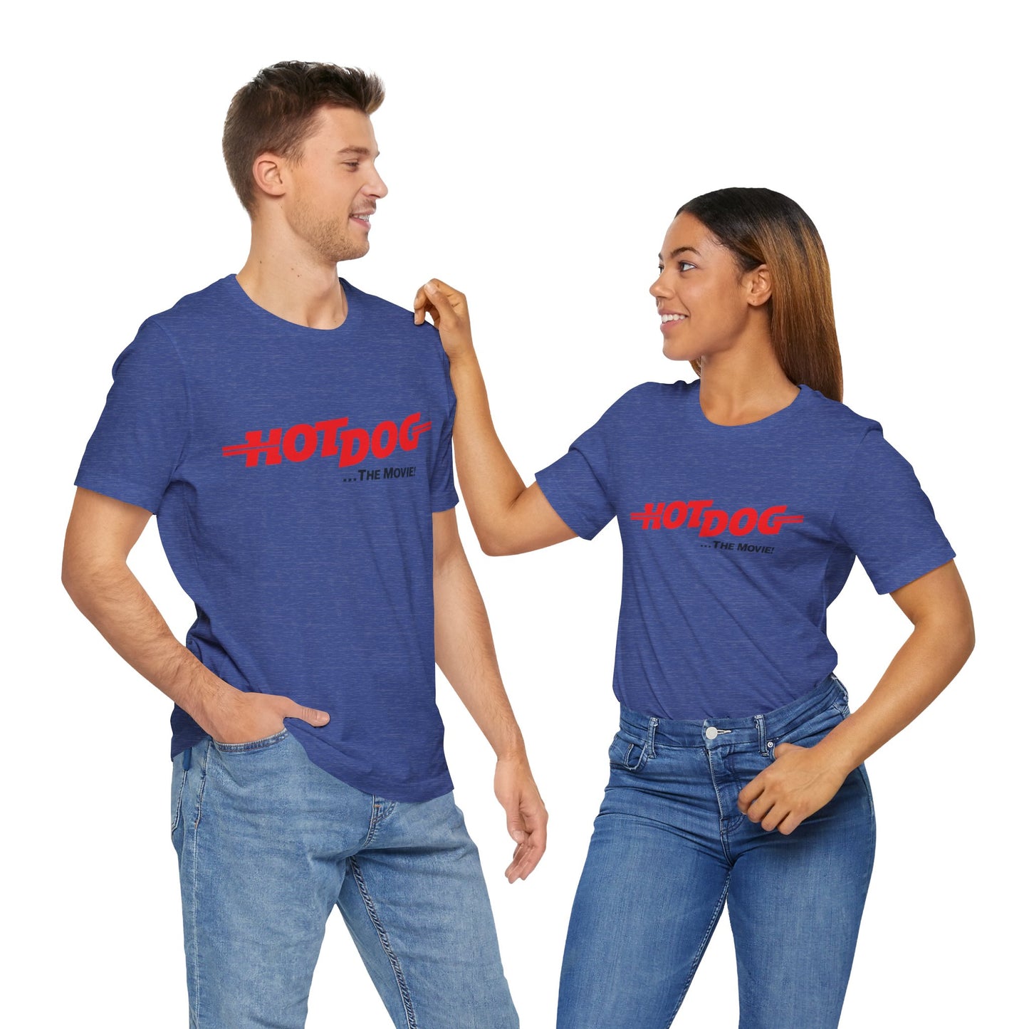 A smiling man and woman interact while wearing matching yellow "Hot Dog The Movie 1984 - Unisex Jersey Short Sleeve Tee" by Printify, featuring bold red "HOT DOG THE MOVIE" text. Their vibrant tees perfectly complement their blue jeans, with the man casually having his hands in his pockets and the woman resting one hand on his shoulder.