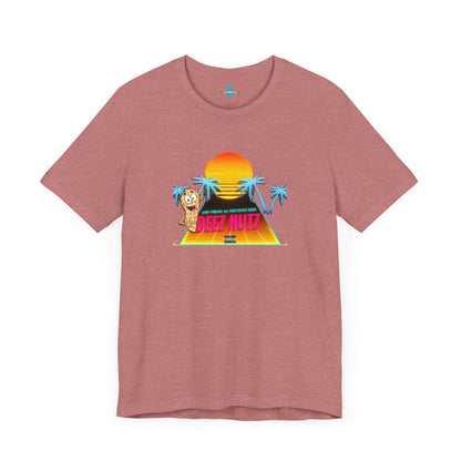 A Printify "Deez Nutz Jerry Pancake and Christopher Robin" t-shirt in purple, featuring a graphic of a sunset over a pyramid with palm trees and an illustration of an anthropomorphic nut holding a sign. The text on the shirt reads, "Just hanging out, cracking open... DEEZ NUTZ." Perfect as a unisex jersey short sleeve tee!